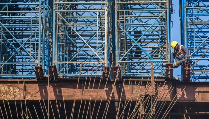 Personnel at work at a road construction site in Mumbai. Construction growth was projected at 9.1 per cent. — AFP/File