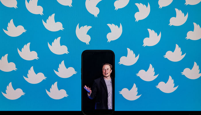 This photo taken on August 5, 2022, shows a cellphone displaying a photo of Elon Musk placed on a computer monitor filled with Twitter logos in Washington, DC. — AFP