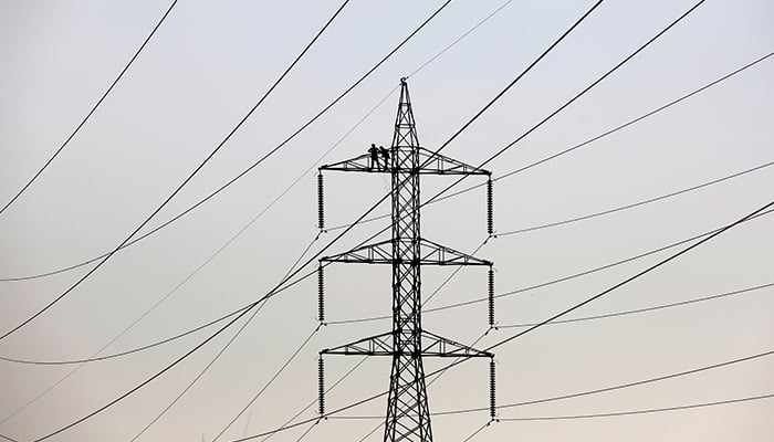 Technicians work to clean power transmission tower in Karachi, December 7, 2018. — Reuters