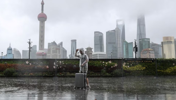 A man with luggage walks in the rain on The Bund as Typhoon In-fa approaches Shanghai, China. — Reuters/File