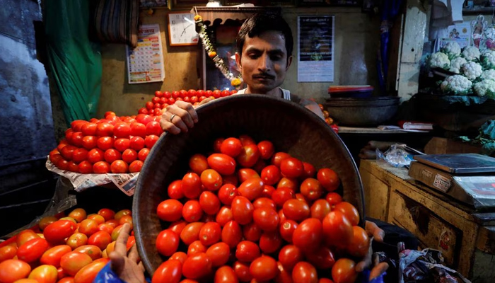 A vendor loads tomatoes in a bag for a customer at a wholesale vegetable market in Mumbai, India, March 14, 2018. — Reuters