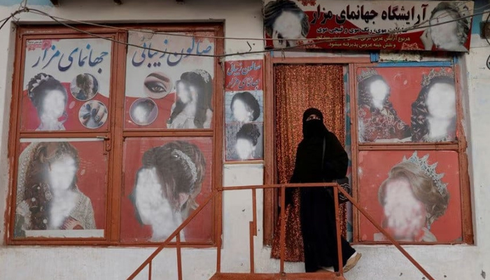 A woman wearing a niqab enters a beauty salon where the ads of women have been defaced by a shopkeeper in Kabul, Afghanistan October 6, 2021. — Reuters