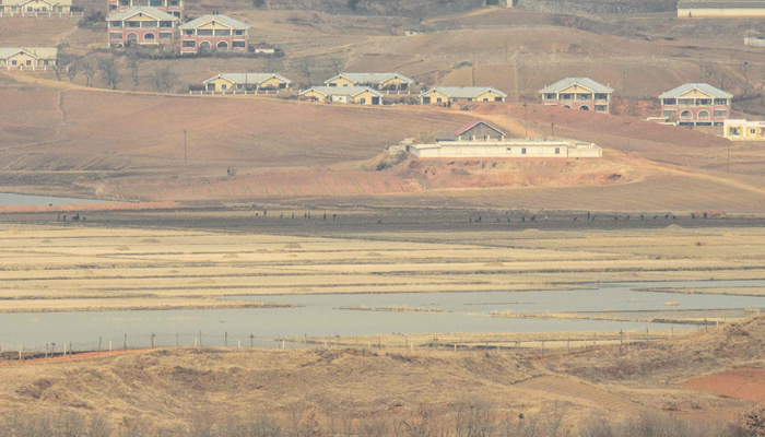 A general view of people working in fields on the North Korean side of the Korean Demilitarized Zone (DMZ), from the Odusan Unification Tower in Paju on March 3, 2023. — AFP