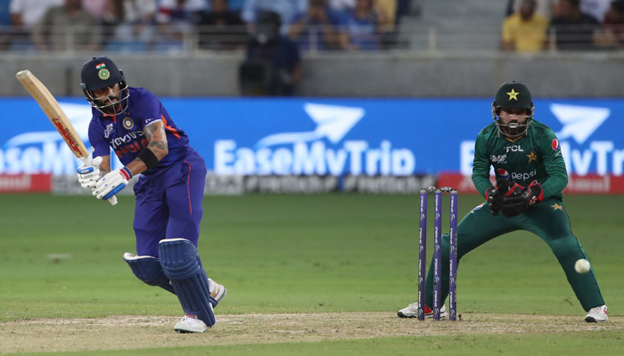 Indian batter Virat Kohli (left) plays a shot as Pakistan wicketkeeper batter Mohammad Rizwan looks on during an India vs Pakistan match in the Asia Cup T20 match in Dubai, UAE in September 2022. — AFP