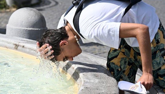 A boy pours water over his head to cool off at the fountain in Piazza del Popolo in Rome. AFP/File