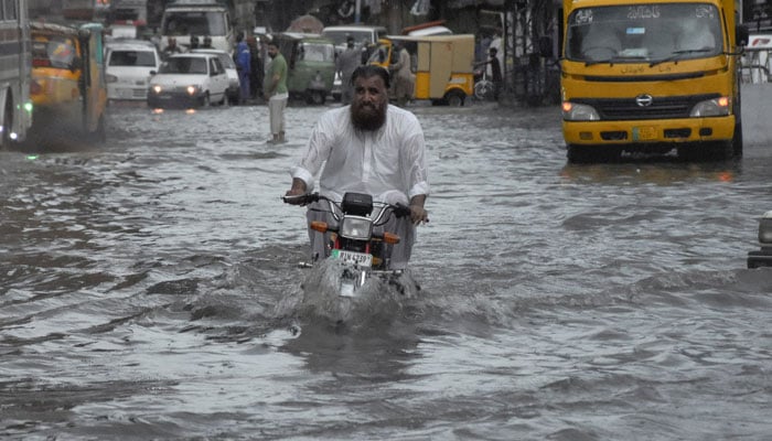 A man rides on a motorcycle amid flood waters along a road during the monsoon season in Rawalpindi, July 19, 2023. — Reuters