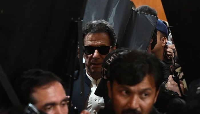 Security personnel with ballistic shields escort PTI Chairman Imran Khan as he leaves after appearing at the Lahore High Court on May 19, 2023. — AFP