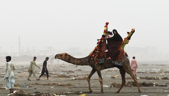 Visitors enjoy a camel ride at Sea View Beach in Karachi, on June 16, 2023. — AFP