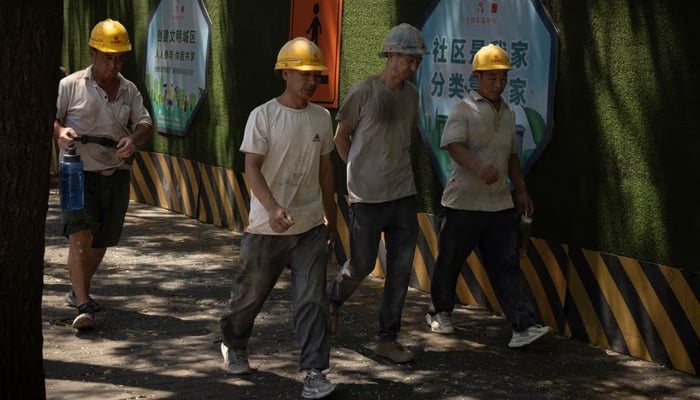 Workers walk in a street in Beijing, China, July 14, 2023. — Reuters