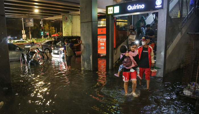 People wade through a flooded street in Manila on July 29, 2023. —  AFP