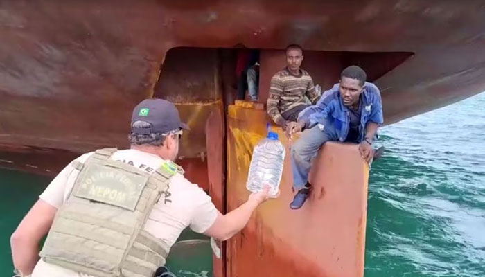 Nigerian migrants are rescued by Brazilian police as they sit on the rudder of a ship after crossing the crossing the Atlantic in this undated frame grab from video. — Reuters/File