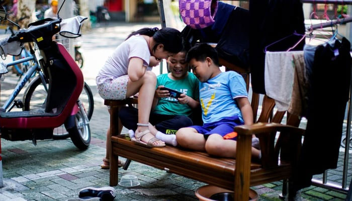 Children look at a phone on a street in Shanghai, China August 28, 2021. — Reuters