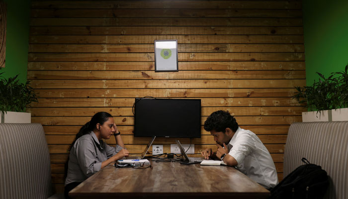 People sit and work on their laptops at Deloittes office in Gurugram, India, June 13, 2023. — Reuters