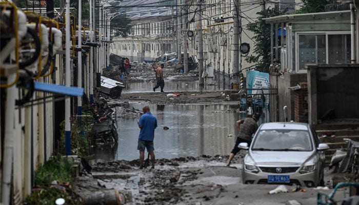 Local residents clean up the street in the aftermath of the flooding at a village following heavy rains in Beijing on August 3, 2023. — AFP/File