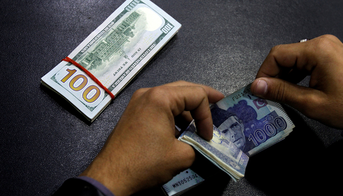 A currency trader counts Pakistani Rupee notes as he prepares an exchange of US dollars in Islamabad. — Reuters