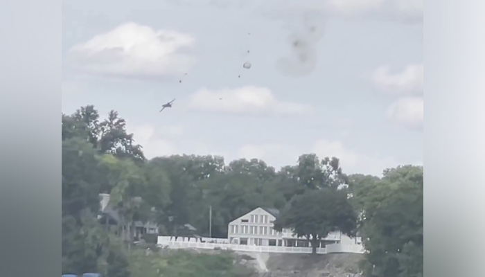 This still taken from a video circulating on social media shows a plane with smoke on its right that came after two pilots ejected the plane when it crashed during Thunder Over Michigan air show. — Twitter/@CBSNews