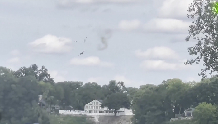 This still taken from a video circulating on social media shows a plane with smoke on its right that came after two pilots ejected the plane when it crashed during Thunder Over Michigan air show. — Twitter/@CBSNews