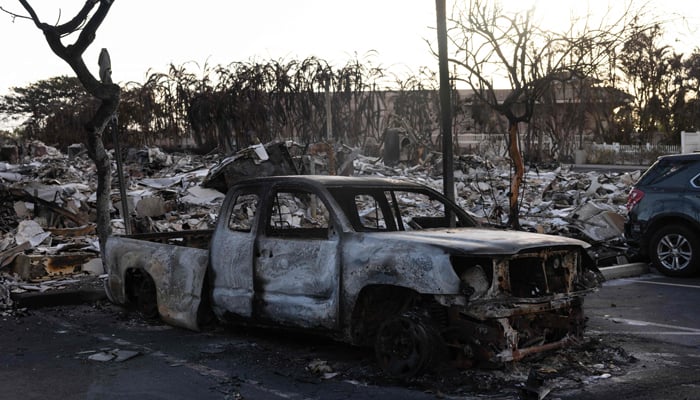 A burnt out car lies in the driveway of charred apartment complex in the aftermath of a wildfire in Lahaina, western Maui, Hawaii on August 12, 2023. — AFP