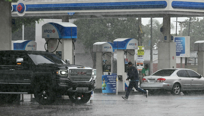 A person runs outside a gas station during heavy rains from Hurricane Hilary, in south Los Angeles, California, on August 20, 2023. — AFP