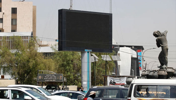 Vehicles drive past a switched-off advertising screen at Kahramana Square in Baghdad on August 20, 2023.—AFP