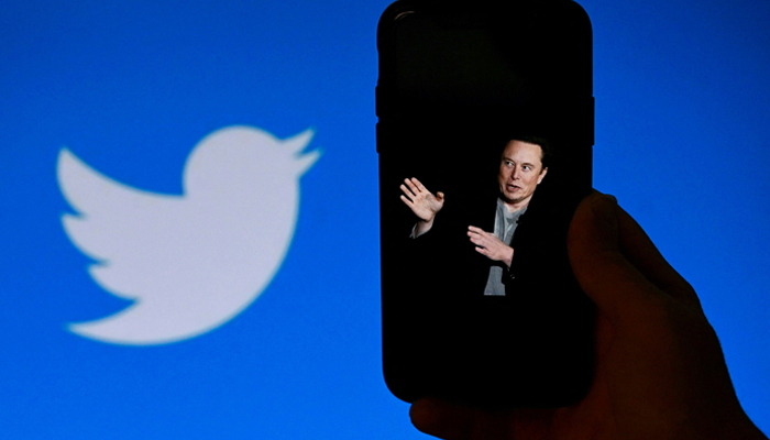 In this photo illustration, a phone screen displays a photo of Elon Musk with the Twitter logo shown in the background, on October 4, 2022, in Washington, DC. — AFP