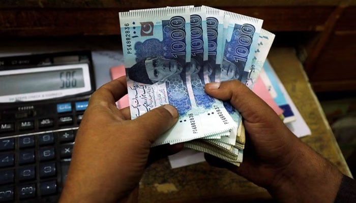 A trader counts Pakistani rupee notes at a currency exchange booth in Peshawar, December 3, 2018. — Reuters