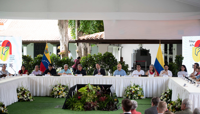 Delegates of Colombias last active guerrilla National Liberation Army (ELN), (L) and Colombian delegates (R), accompanied by Venezuelas FM Yvan Gil (C), applaud while taking part in the framework of peace talks in Caracas on September 4, 2023. — AFP