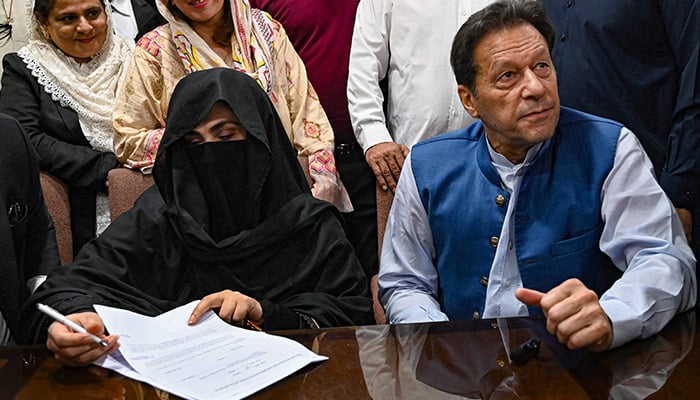 PTI Chairman Imran Khan (right) along with his wife Bushra Bibi looks on as he signs surety bonds for bail in various cases, at a registrar office in the High court, in Lahore on July 17, 2023. — AFP