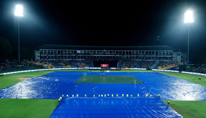 Ground staff covers the field as it pours heavily at the Pallekele Cricket Stadium. — X/@TheRealPCB