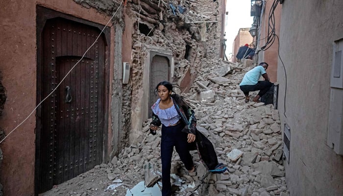 A woman walks with her belongings through the rubble in the earthquake-damaged old city in Marrakesh on September 9, 2023. — AFP