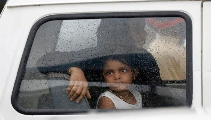 A girl looks out of a car window with raindrops during the seasons first monsoon rain in Karachi on July 6. 2020 — Reuters