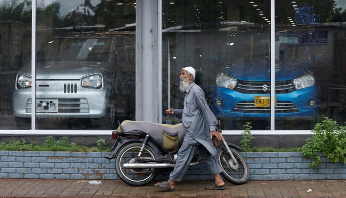 A man walks past a Suzuki outlet, displaying cars in Karachi on July 27, 2022. — Reuters