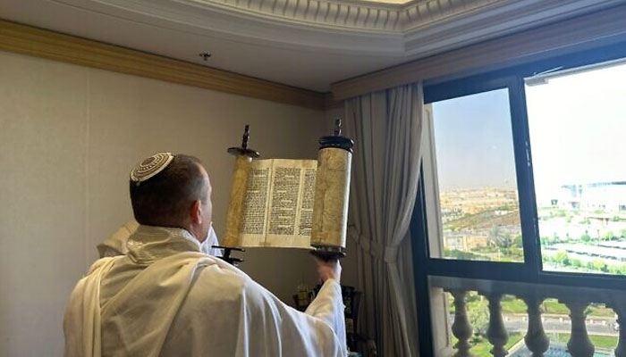 A member of Communications Minister Shlomo Karhis delegation holds up a Torah scroll during a morning prayer service in Riyadh, Saudi Arabia, October 3, 2023. — Spokesmans Office, Communications Ministry