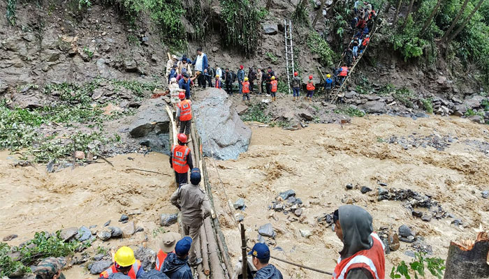 Stranded tourists crossing a river with the help of Border Roads Organisation personnel in Chungthang, in the Indian state of Sikkim, due to landslides amid torrential rains. — AFP/File