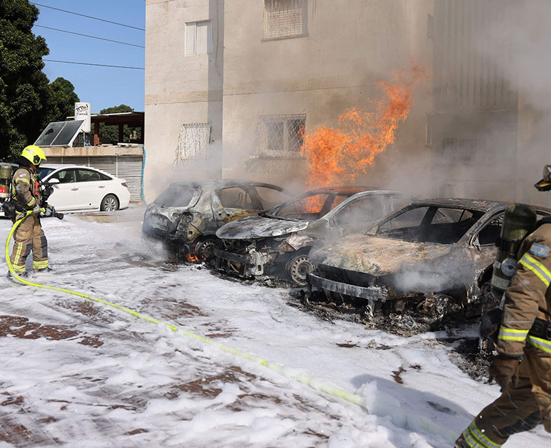 A member of Israeli security forces tries to extenguish fire on cars following a rocket attack from the Gaza Strip in Ashkelon, southern Israel, on October 7, 2023. — AFP