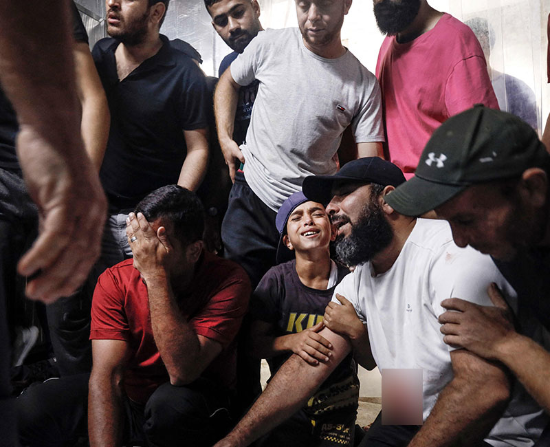 Family members and relatives mourn over the bodies of Palestinian fighters killed in the latest inflitration operation into Israel, at the mortuary of a hospital in Gaza City on October 7, 2023. — AFP