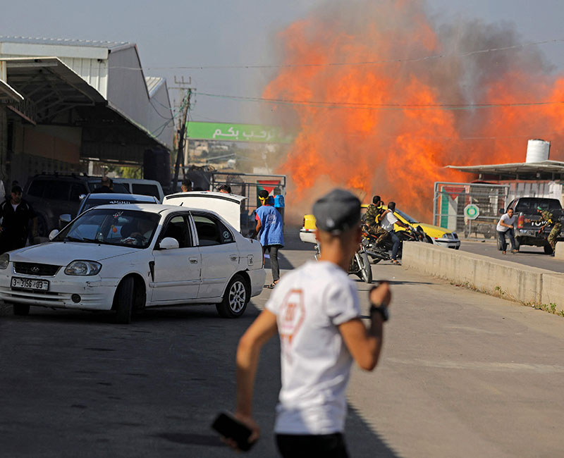 Palestinians and fighters from the Ezzedine al-Qassam Brigades run towards the Erez crossing between Israel and the northern Gaza Strip on October 7, 2023. — AFP