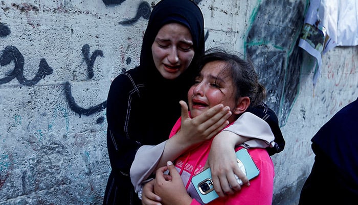 The daughter of Zakaria Abu Maamar, a member of Hamas political office, is comforted as she cries during her fathers funeral, after he was killed in an air strike, in Khan Younis, in southern Gaza Strip, October 10, 2023. — Reuters