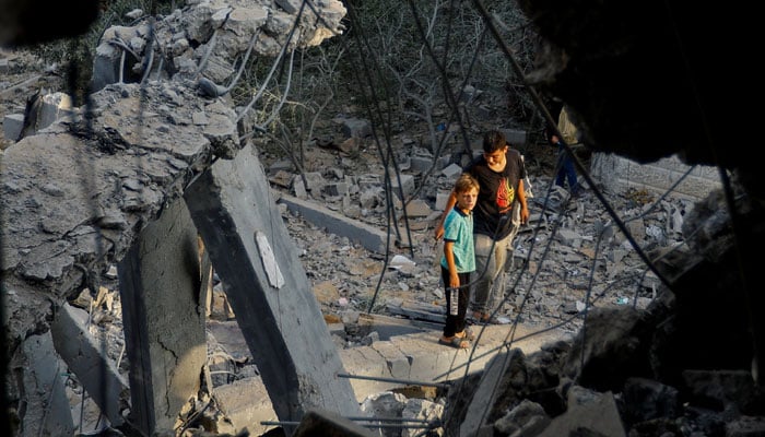 Palestinians stand on the rubble near a damaged house, following Israeli strikes, in Khan Younis in the southern Gaza Strip October 11, 2023. — Reuters