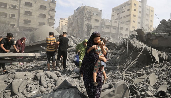 Palestinians in Gaza city inspect the damage following an Israeli airstrike, 9 October 2023. AFP