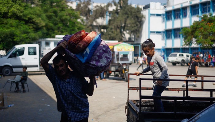 A Palestinian man who fled his home amid Israeli strikes, carries belongings to shelter in a United Nations-run school, in Gaza City October 8, 2023. — Reuters