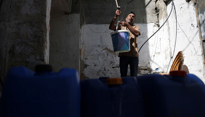 A man attaches a bucket of water to a hook to refill a water tank at a home in the Rafah refugee camp, in the southern Gaza Strip on October 15, 2023. — AFP