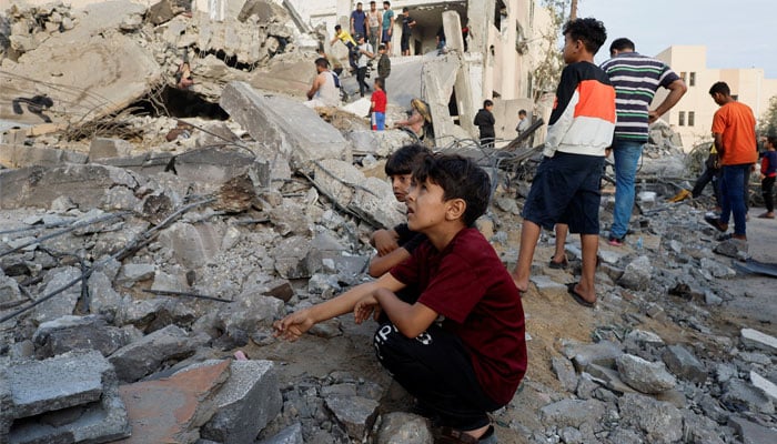 Palestinian children sit amidst the rubble as others inspect under the rubble of a building destroyed by Israeli strikes in Khan Younis in the southern Gaza Strip, October 17, 2023. — Reuters