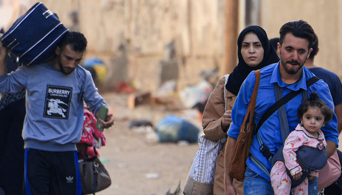 Palestinians with their belongings flee from their homes following Israeli airstrikes in Gaza City on Friday. — AFP