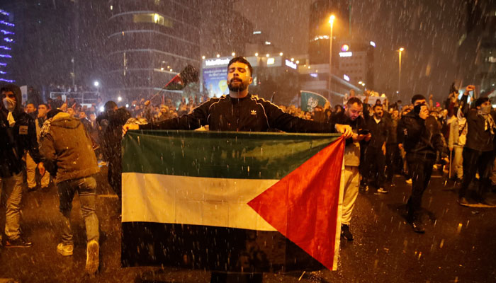 A man holds a Palestinian flag as Turkish riot police use water cannon to disperse pro-Palestinian demonstrators during a protest, near the Israeli Consulate in Istanbul, Turkey October 17, 2023. — Reuters