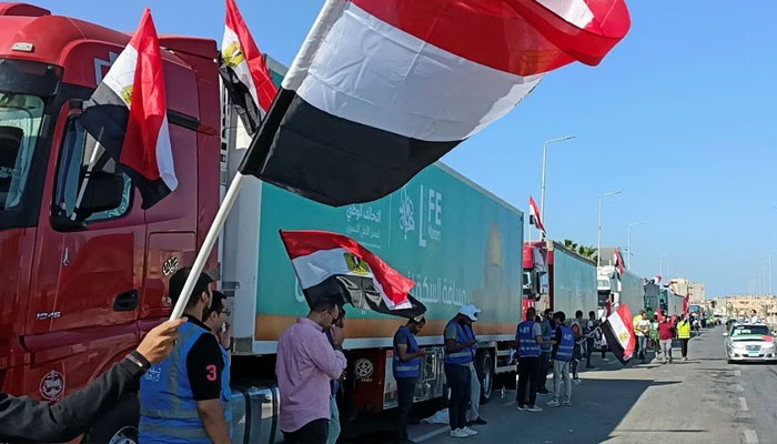 People with Egyptian flags cheer next to a convoy of trucks carrying humanitarian aid to Palestinians by Egyptian NGOs, as they wait for an agreement on the Rafah border crossing to enter Gaza, amid the ongoing conflict between Israel and the Palestinian Islamist group Hamas, in the city of Al-Arish in Egypts Sinai peninsula, Egypt, October 15, 2023. —Reuters