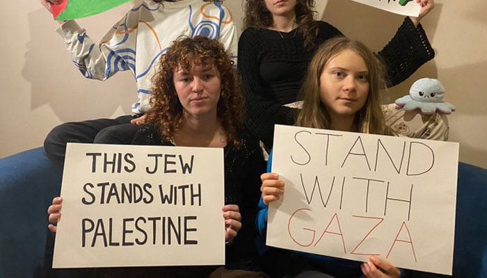 Greta Thunberg along with others holding a poster that reads. stand with Gaza.—X@GretaThunberg