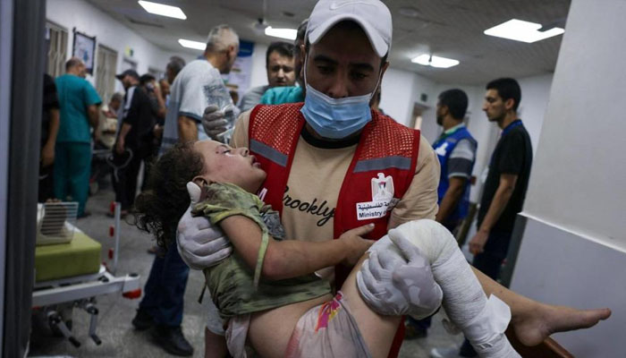 An emergency responder carries a wounded child in a hospital following Israeli airstrikes in Rafah, Gaza this week. — AFP