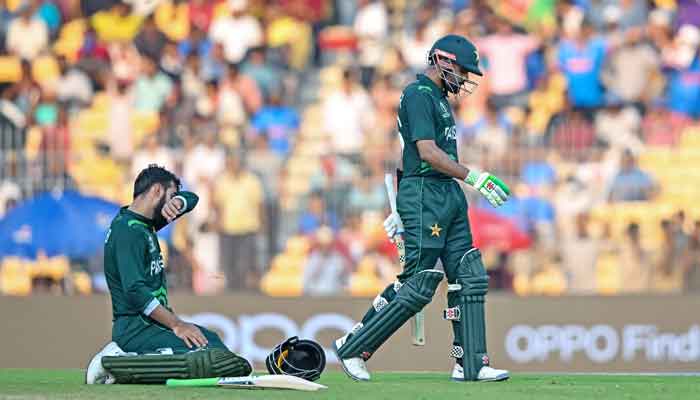Shadab Khan rests on the ground as captain Babar Azam (R) walks back to the pavilion after his dismissal during the 2023 ICC Men´s Cricket World Cup one-day international (ODI) match between Pakistan and Afghanistan at the MA Chidambaram Stadium in Chennai on October 23, 2023. —AFP