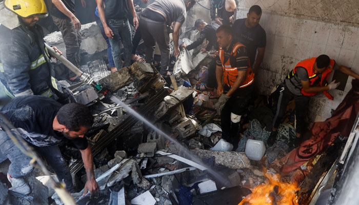 Emergency services extinguish a fire as Palestinians search for casualties at the site of an Israeli strike on a house, in Khan Younis, in the southern Gaza Strip, October 24, 2023. — Reuters